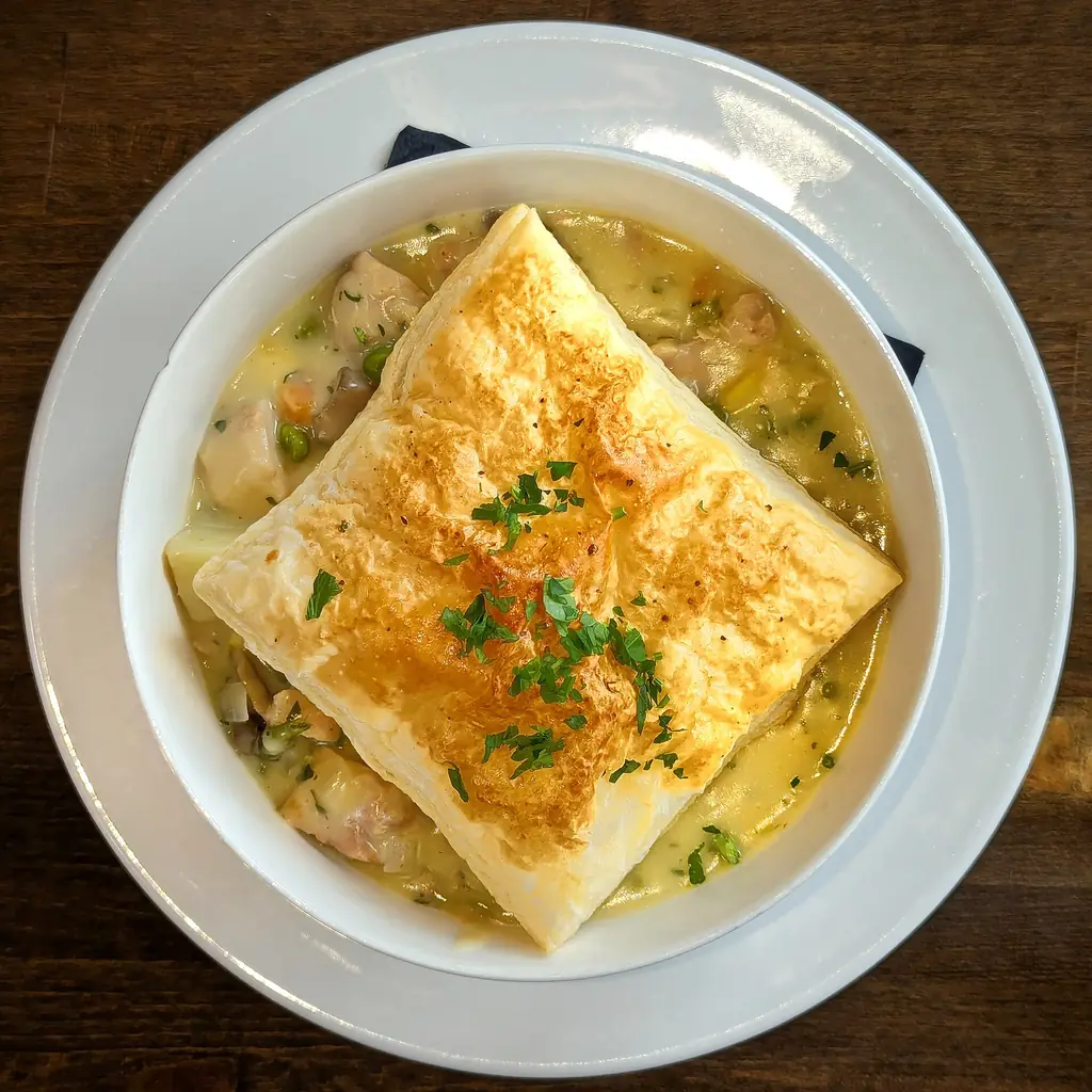 Chicken pot-pie filling served in a bowl beneath a square pastry lid.