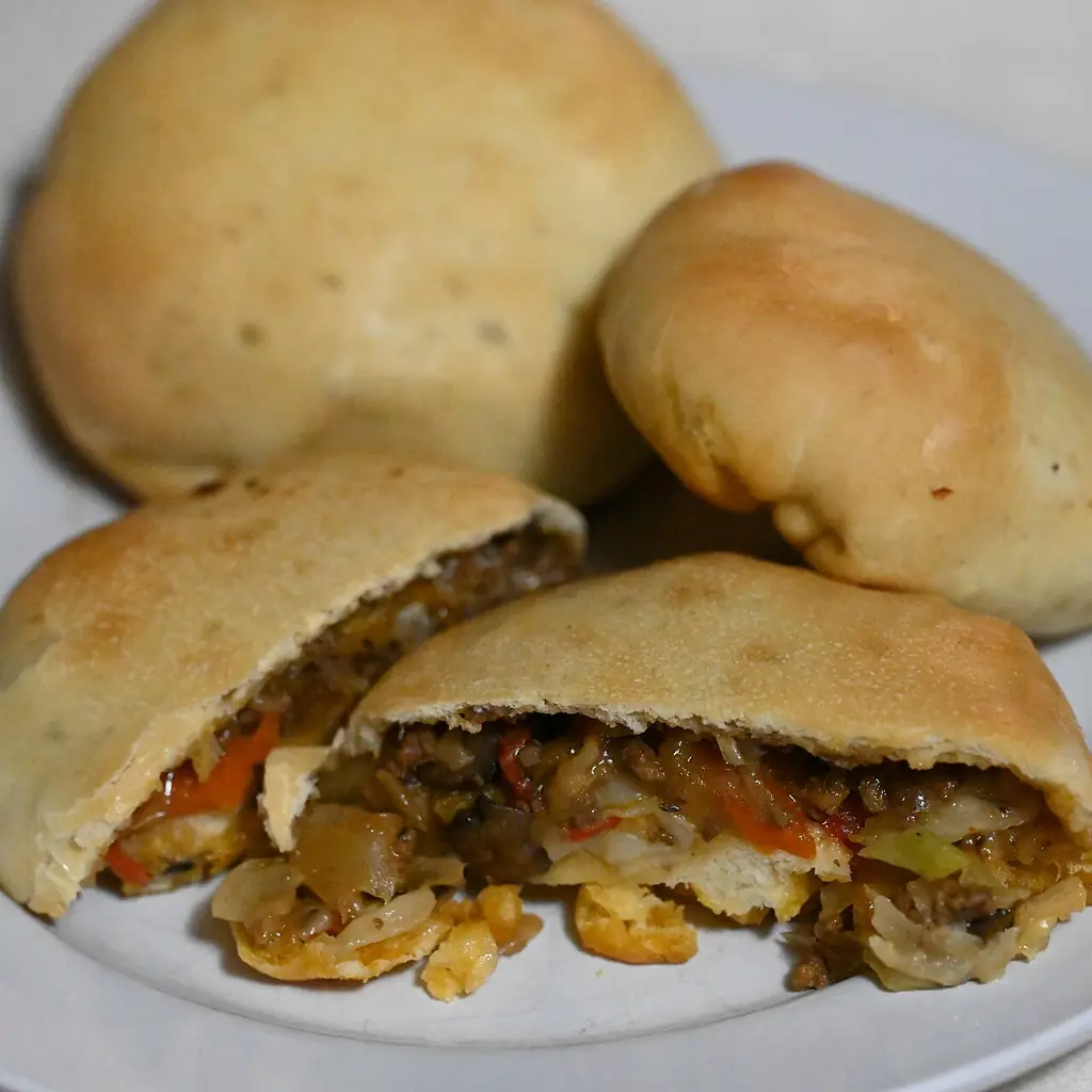 Bierocks with one cut open to show the meat and cabbage filling.