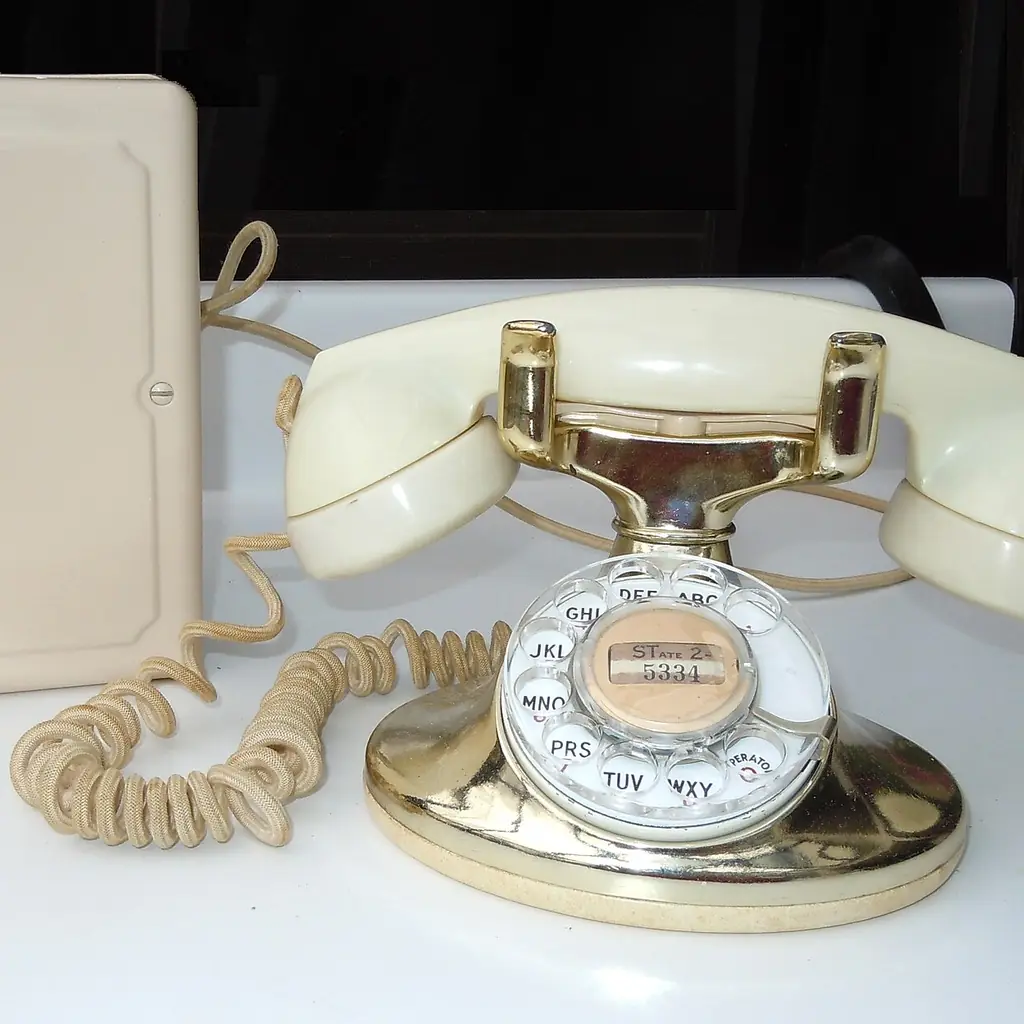 A cream and gold Western Electric rotary telephone with its separate telephone subset.