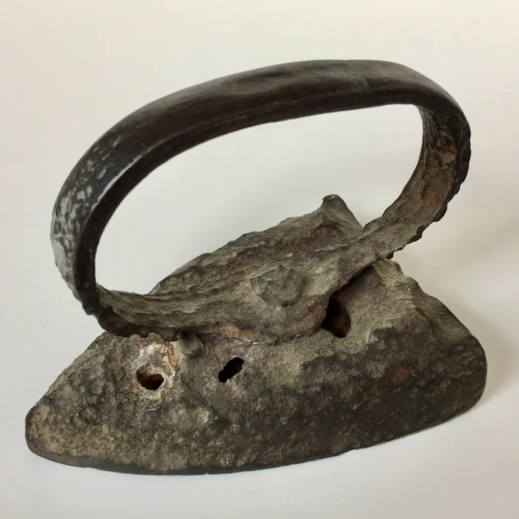 An antique solid sad iron with a curved handle.