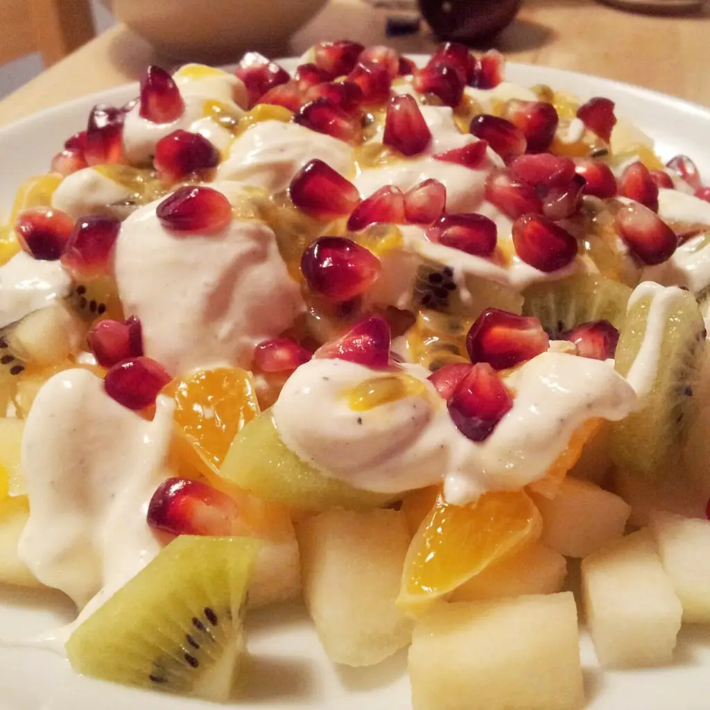 A bowl of mixed fruit salad with creamy dressing.