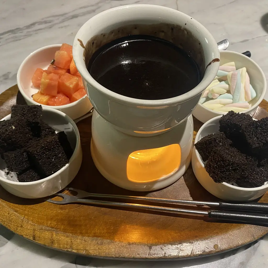 A candle-warmed chocolate fondue pot with fruit and other dipping pieces.