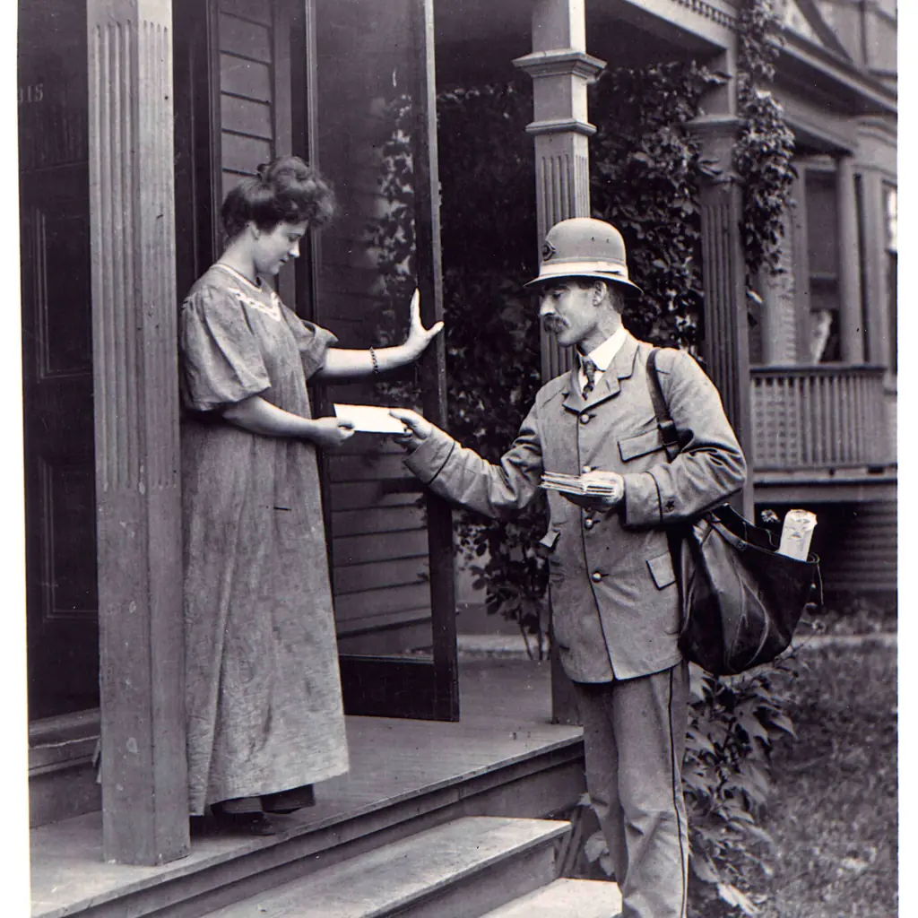 A letter carrier handing mail to a woman on her porch.