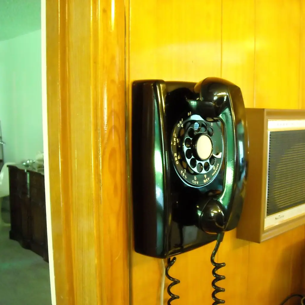 A black rotary dial telephone mounted on a wall.